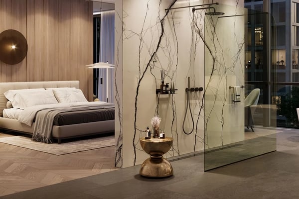 Modern master bedroom and open bathroom with bed, decorative pendant lights, marble walls with branch accents, and glass shower enclosure.